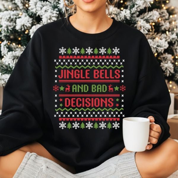 Black holiday sweatshirt with cross-stitch style text that reads โJingle Bells and Bad Decisionsโ in red and green with snowflake and reindeer accents.