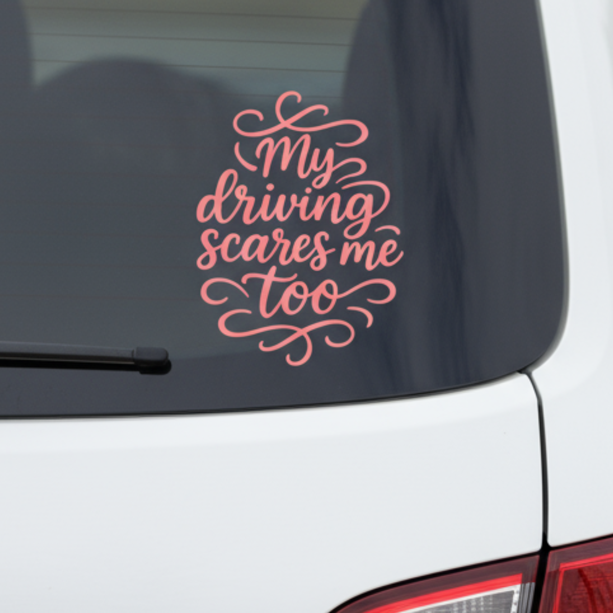 Pink vinyl car decal that reads “My driving scares me too” displayed on the rear window of a white vehicle.