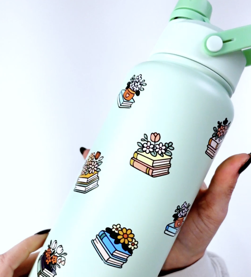 Mint green water bottle decorated with multiple floral book UV DTF stickers applied around the surface.