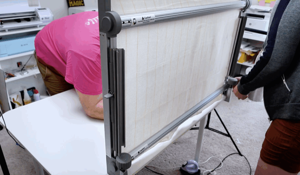 Aluminum clawlab tufting frame attached to a table with primary tufting cloth stretched across the frame.