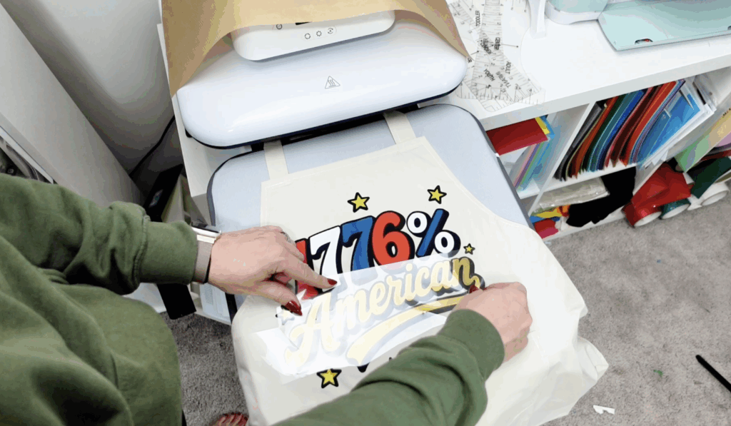 Positioning layered HTV pieces into knockout cutouts on a patriotic apron design.