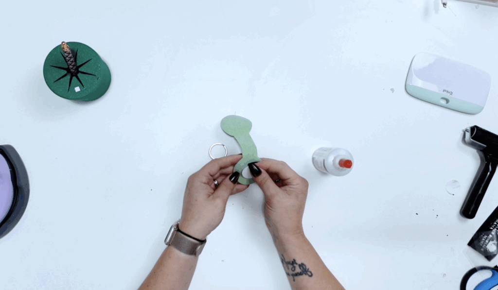 Hands positioning a faux leather NFC keychain around a metal key ring before gluing.