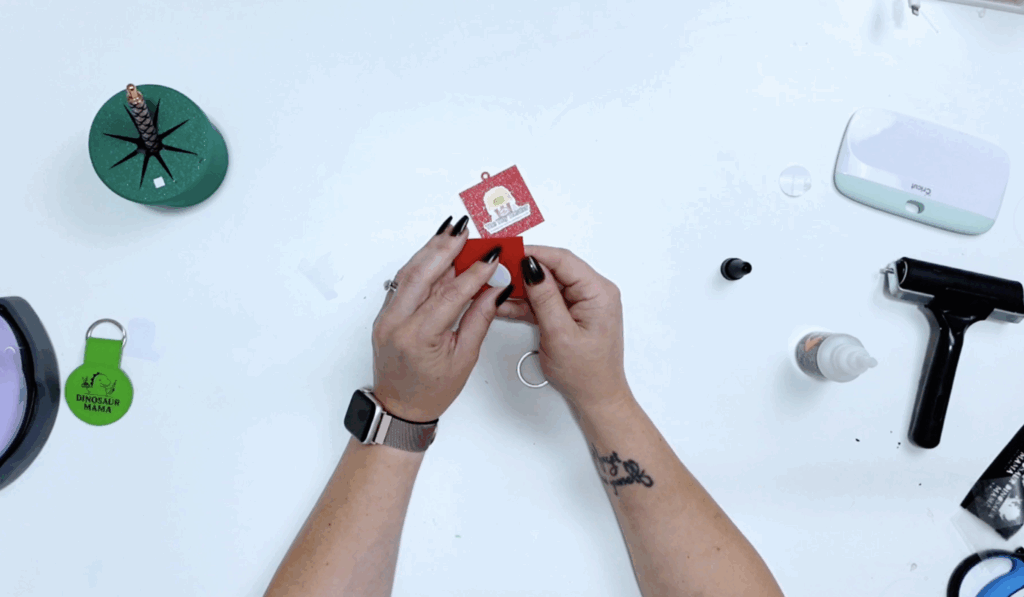 Red 3D printed NFC keychain being assembled with a custom sticker for small business promotion.